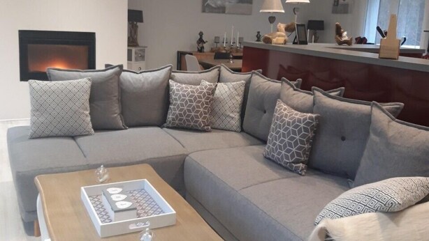 A modern living room with a grey sectional sofa, a wooden coffee table, and a fireplace. - Riverfront house with swimming pool and magnificent view of the mountains and cliffs. (Trèves)