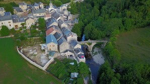 An aerial view of a village with stone buildings, a bridge, and a river. - Riverfront house with swimming pool and magnificent view of the mountains and cliffs. (Trèves)