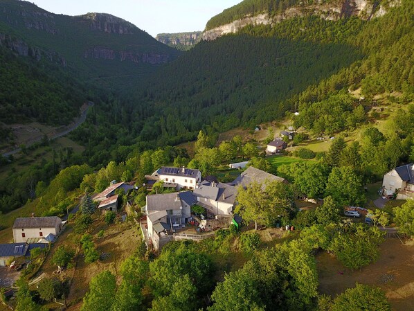 A rural village with houses surrounded by lush greenery and mountains in the background.