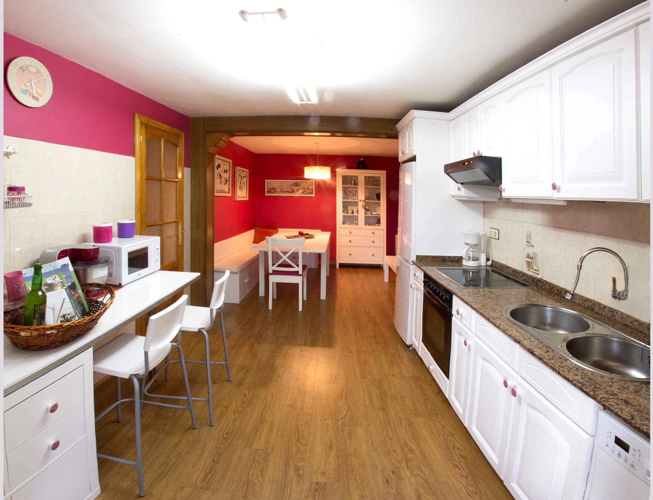 Una cocina compacta con gabinetes blancos, microondas, lavabo y comedor con mesa y sillas.