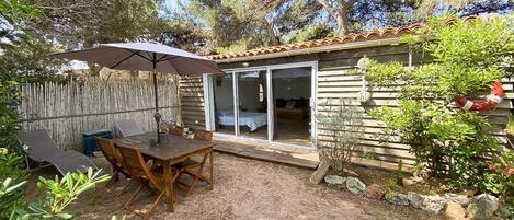 Une cabane en bois dotée d’un patio, d’une table à manger et d’un espace salon abrité.