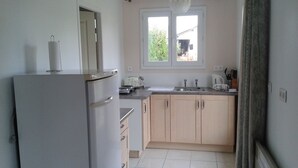 Eine kleine Küche mit Kühlschrank, Fenster und Grundausstattung.