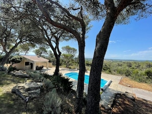 A house with a swimming pool surrounded by trees and a view of the countryside.
