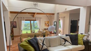 A spacious living room with a large sofa, a dining area, and a view of the outdoors. - Modern villa - 5 bedrooms, in Uchaux village - private pool & amazing views (Uchaux)