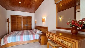 A bedroom with a wooden bed, bedside tables, a mirror, and a vase with flowers. - Albufeira, Sea Balcony (11) (Albufeira)