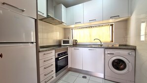 A compact kitchen with white cabinets, a microwave, a coffee maker, a sink, and a washing machine. - Albufeira, Sea Balcony (11) (Albufeira)