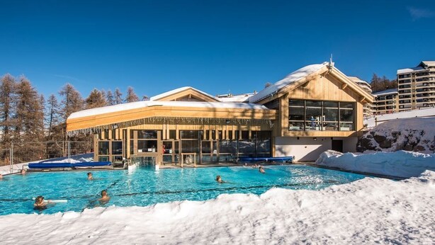 Un hotel con zona de piscina, rodeado de nieve.