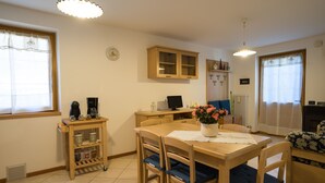 Un coin repas comprenant une table en bois, des chaises, un petit meuble et un vase à fleurs.