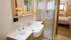 Une salle de bain moderne avec une douche à parois de verre, un meuble-lavabo à deux vasques et un miroir au-dessus du lavabo.