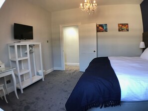 A bedroom with a bed, a TV on a stand, a wardrobe, and a door leading to another room. - Elegant apartment steps from Roman Baths & Abbey (Bath)