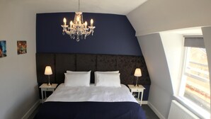 Une chambre à coucher avec un grand lit, deux lampes de chevet, un lustre et une fenêtre donnant sur un beau paysage.