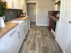 A modern kitchen with white cabinets, a wooden countertop, and a red refrigerator. - Elegant apartment steps from Roman Baths & Abbey (Bath)