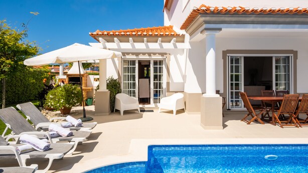 Zona piscina con sedie a sdraio, un tavolo da pranzo e una veranda coperta.