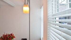 A modern dining area with a white table, black chairs, a vase with flowers, and a hanging light fixture.