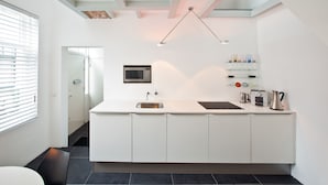 A modern kitchen with white cabinets, a stainless steel sink, a microwave, and a coffee maker.