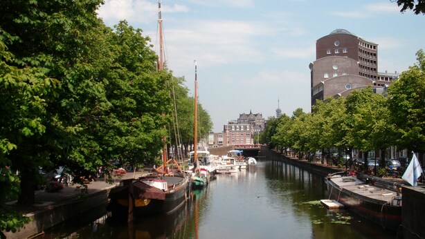 A canal lined with trees and boats, with buildings in the background.