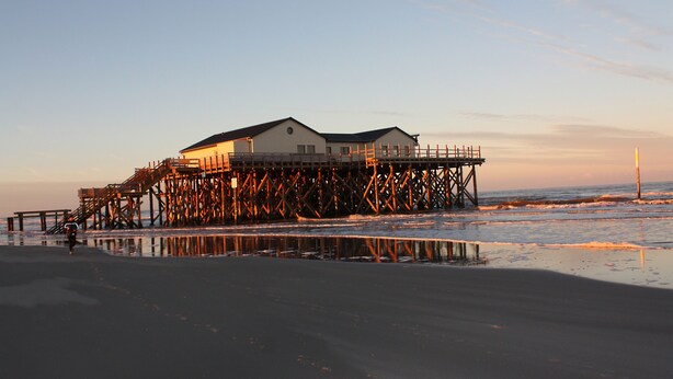 A pier structure with a building on top, extending into the water.
