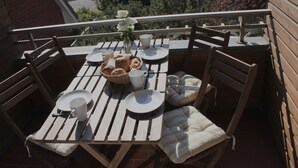 A wooden outdoor dining set with chairs, a table, and a basket of bread.