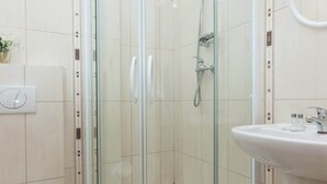 Une salle de bain moderne avec une douche à parois de verre, des toilettes blanches et un lavabo avec un miroir.
