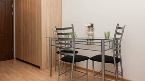 Un coin repas avec une table en verre, quatre chaises, un vase de fleurs et une armoire en bois.