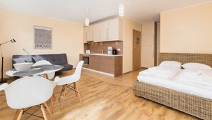 Een compacte woonruimte met een kitchenette, een eethoek met een tafel en stoelen, een bank en een bed.