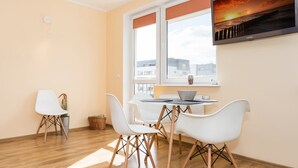 Een moderne eethoek met een tafel, stoelen en een aan de muur bevestigde televisie.