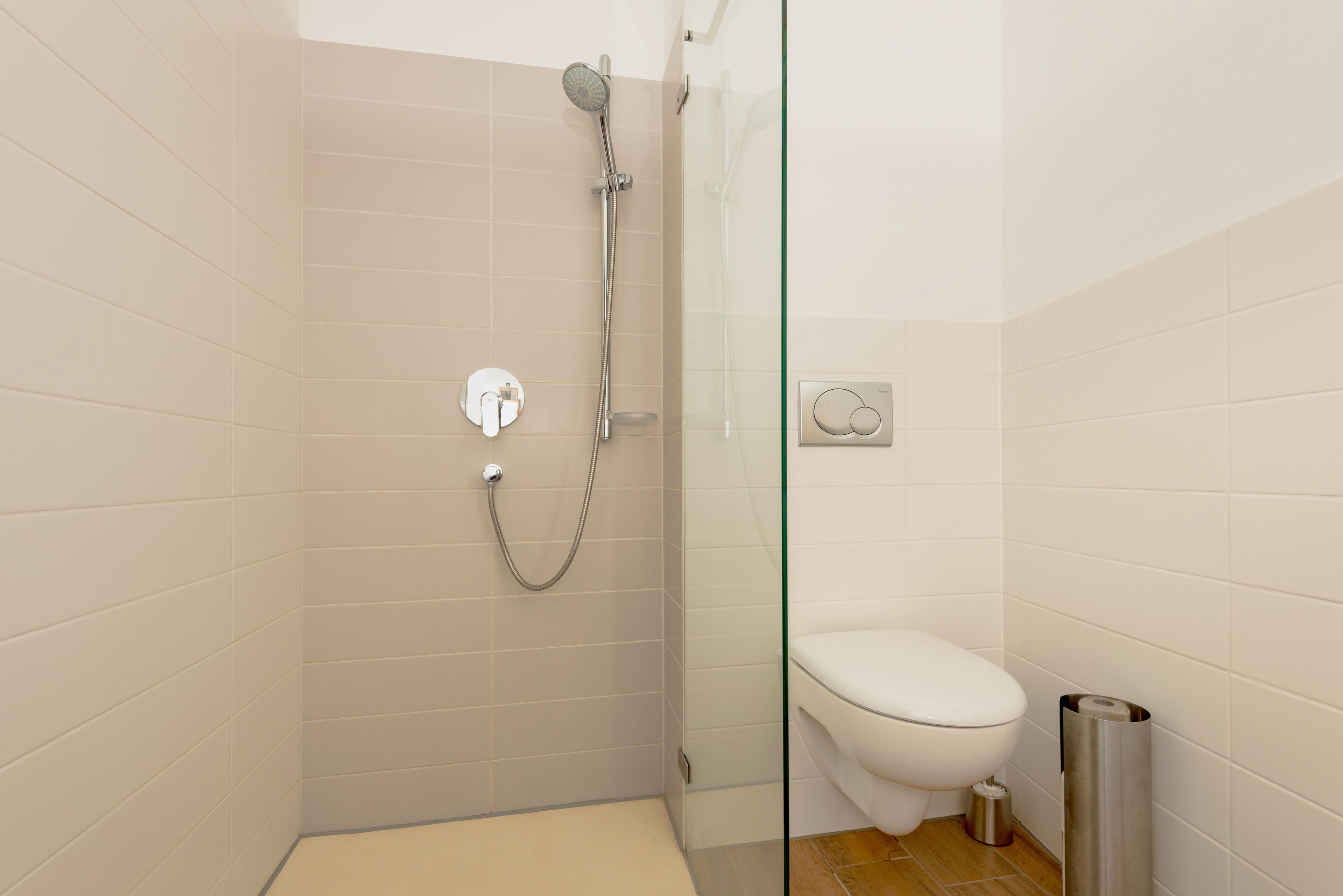 Un baño moderno con cabina de ducha de vidrio, inodoro y cubo de basura.