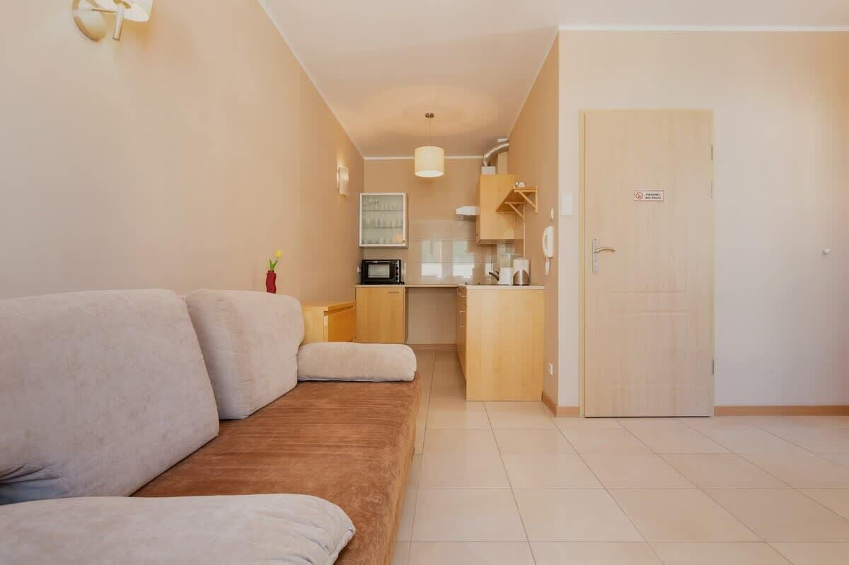 Un salon moderne avec un canapé, un petit coin cuisine et une porte.