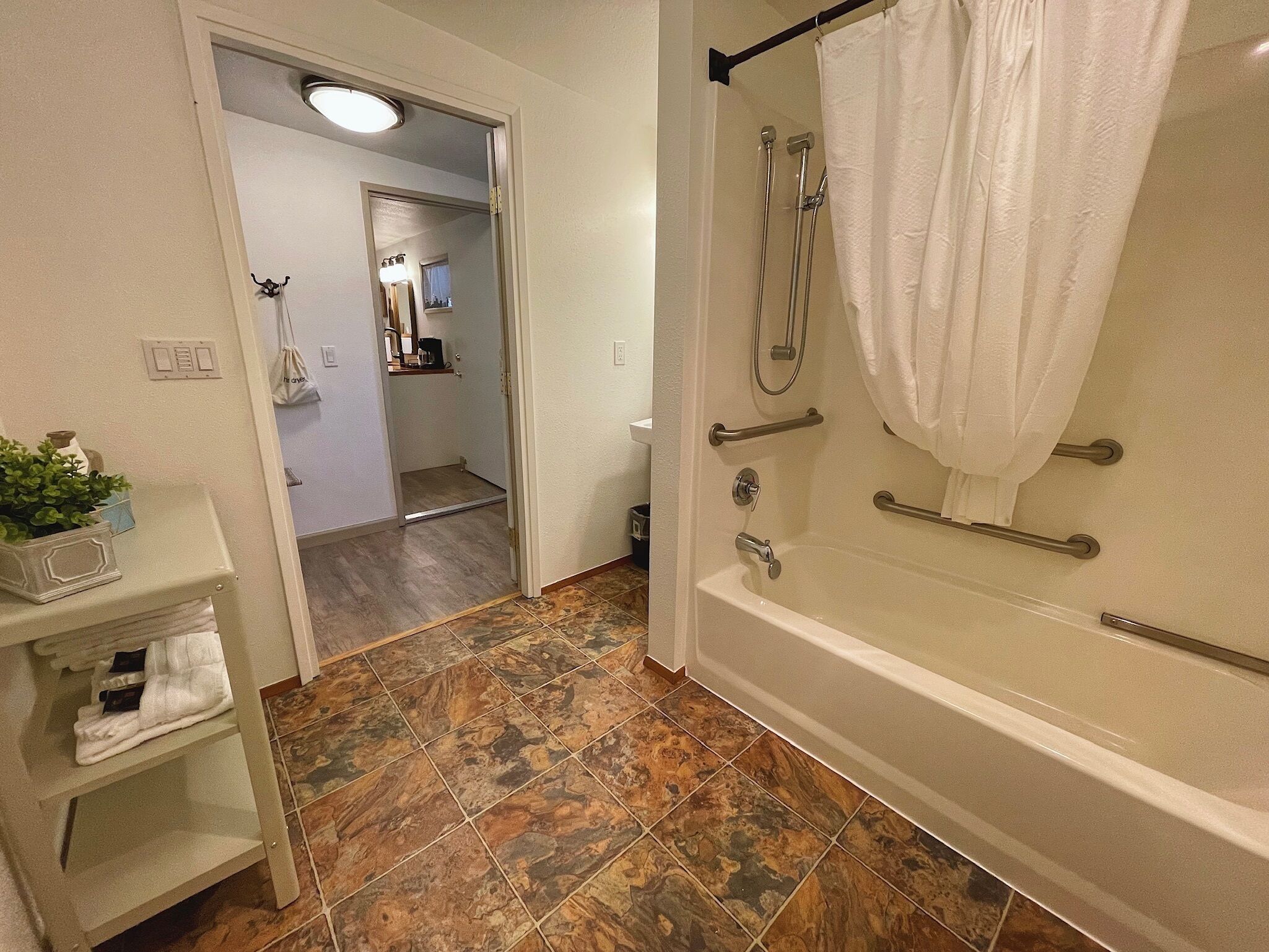 A bathroom with a bathtub, shower, and a sink area.