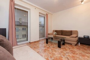A living room with a sofa, a glass coffee table, and a TV. - Cozy Studio | Balcony | Close to Railway Station (Świnoujście)