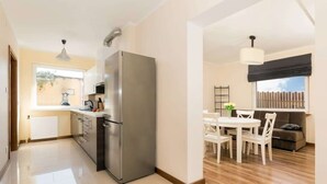 Una cocina moderna con un refrigerador grande, un comedor con mesa y sillas, y vista al exterior.