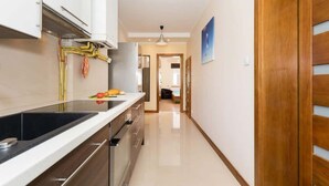 Una cocina moderna con una encimera larga, horno empotrado y un expositor colgante para carnes.