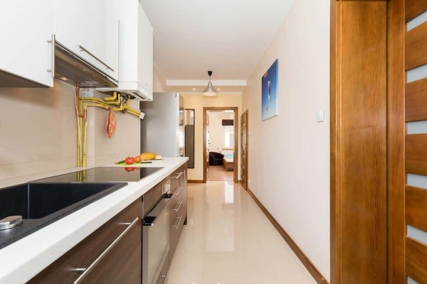 A view of the kitchen from a different angle. Brown and white cabinets. Carny sink and hob.