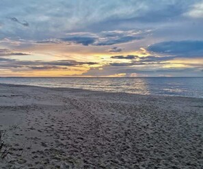 A beach with footprints in the sand and a sunset in the background.