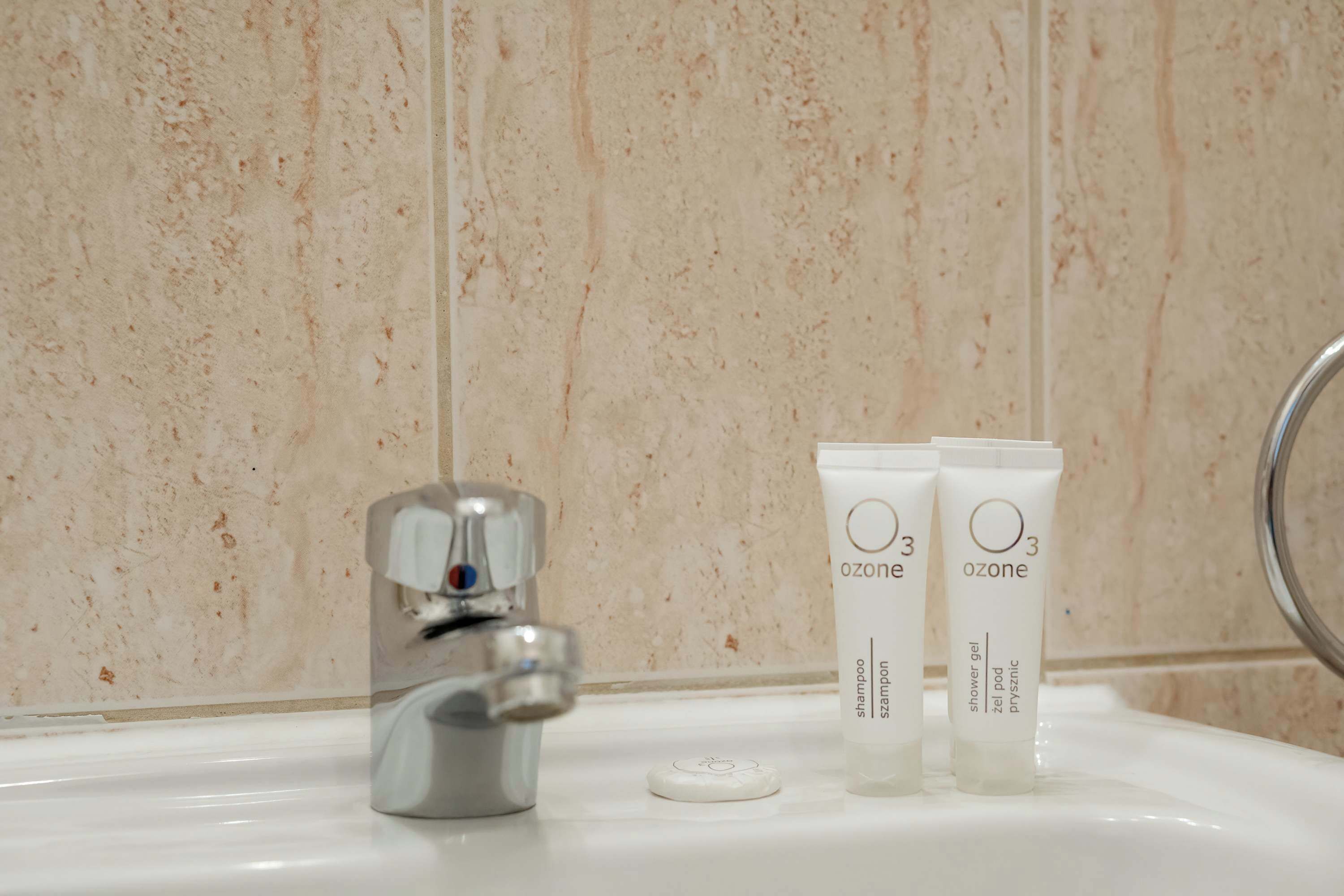 Un lavabo de salle de bain avec deux tubes de gel douche de la marque Ozone et un bouchon.