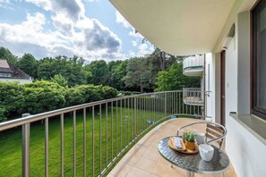 A balcony with a glass table, chairs, and a small potted plant.