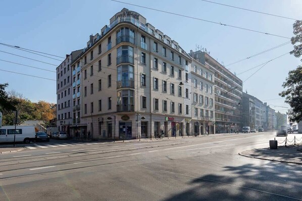 Un hotel de varios pisos con una entrada en esquina, grandes ventanas y un espacio comercial en la planta baja.