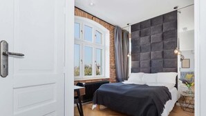 Un dormitorio con cama, ventana, radiador y escritorio.