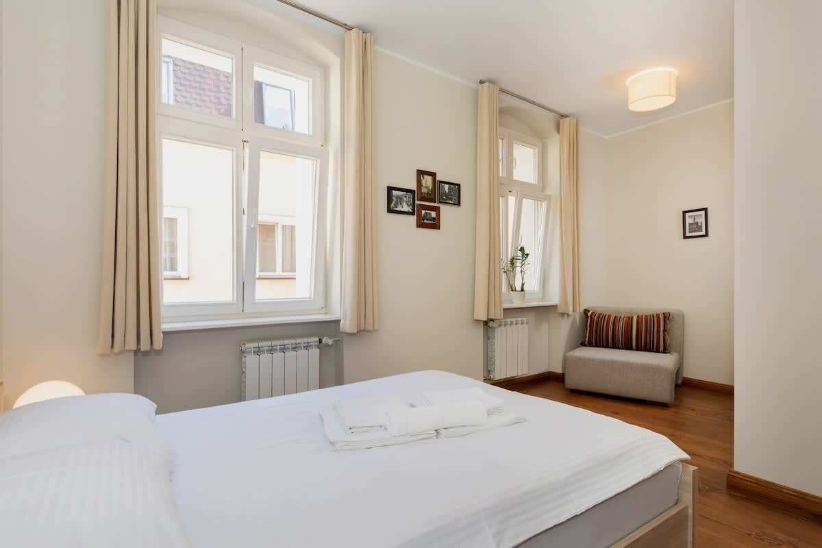 Habitación de hotel con cama, sofá y ventana con cortinas.