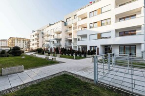 Un immeuble d’appartements moderne doté de nombreux balcons, d’une cour intérieure et d’une pelouse bien entretenue.