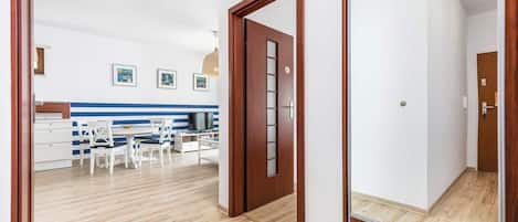 Een moderne keuken met witte kastjes, een eettafel met stoelen en een televisie.