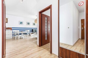 Une cuisine moderne avec des meubles blancs, une table à manger avec des chaises et un téléviseur.