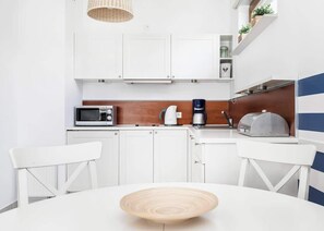 A modern kitchen with white cabinets, a microwave, a coffee maker, and a toaster.