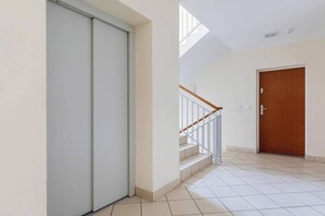Un intérieur épuré et moderne, avec un escalier, une porte coulissante et une porte en bois.
