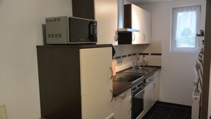 Una cocina compacta con microondas, estufa y lavamanos.