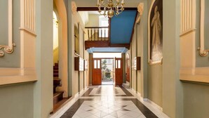 A grand hallway with a tiled floor, a staircase, and a chandelier. - Bright Apartment in the Center | 500 m from the Old Town Square (Poznan)