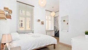 A bedroom with a bed, bedside table, lamp, and a potted plant. - Bright Apartment in the Center | 500 m from the Old Town Square (Poznan)