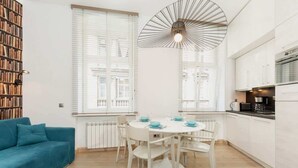 A modern kitchen with white cabinetry and a dining area with a round table and chairs. - Bright Apartment in the Center | 500 m from the Old Town Square (Poznan)