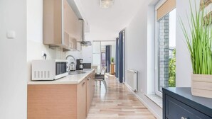 A modern kitchen with a microwave, coffee maker, and wooden cabinets.