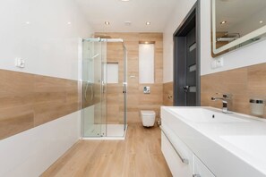 A modern bathroom with a glass shower enclosure, a white sink, and a dark door. - Dom Viking Kołczewo | Stylish House | Four Bedrooms (Domyslów)
